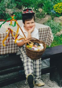 Fiú ül a padnál egy kosár húsvéti tojással